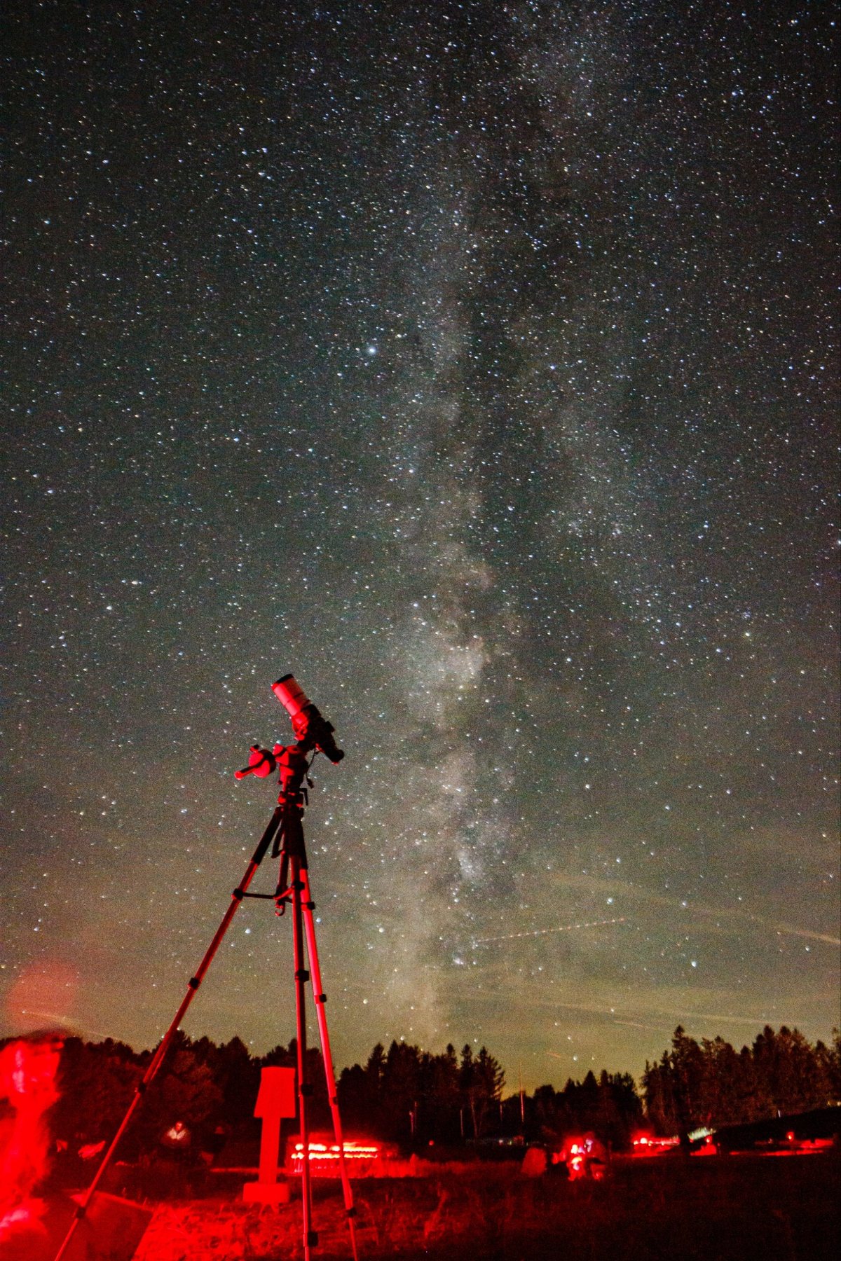 The refractor on its tracker silhouetted against the Milky Way, lit by red light