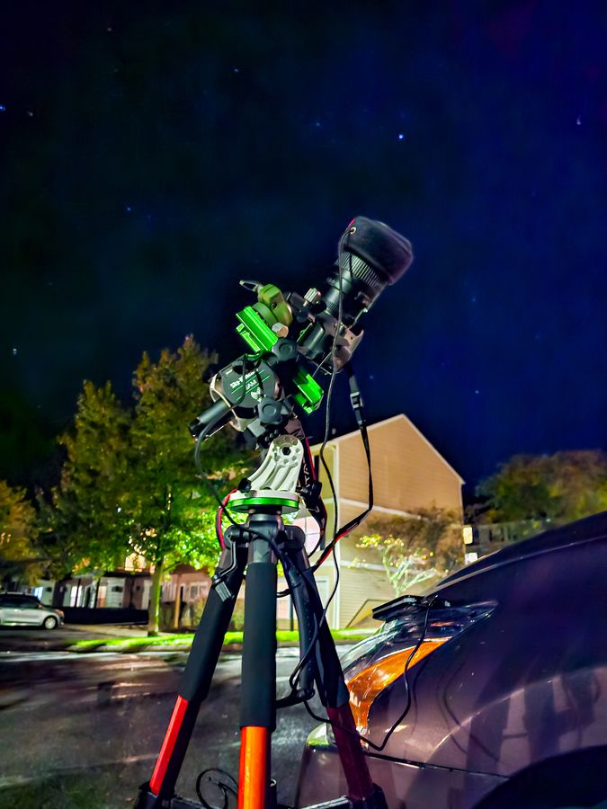A star tracker and camera lens set up in a driveway at night