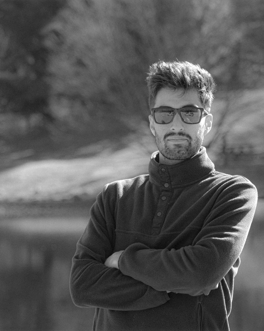 Black and white portrait of Kasra Sinaei by a lake